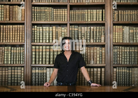 Mann vor Bücherregal voll von alten Büchern Stockfoto