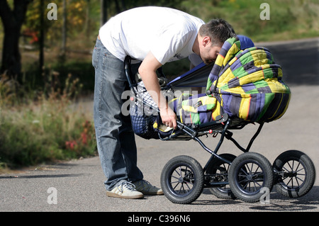 Ein Mann spielt mit seinem Baby im Kinderwagen Stockfoto