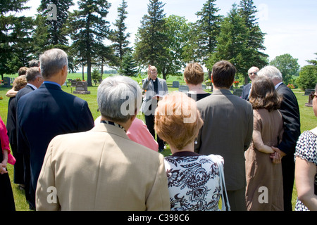 Minister Durchführung Graveside Einlieferung bei einer Beerdigung vor Freunden und Familie auf dem Friedhof. St James Minnesota MN USA Stockfoto