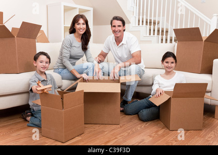 Familie, Eltern, Sohn und Tochter, Kisten auspacken und der Umzug in ein neues Zuhause. Stockfoto