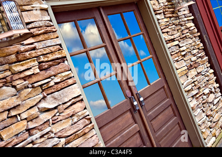 Holztür in einer Felswand mit Reflexion des Himmels und der Wolken. Stockfoto