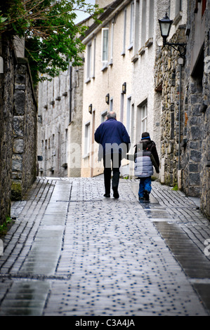 Alter Mann und junge Burschen, die hand in hand gehen hinunter die Straße.  Generationen zusammen schreiten. Stockfoto