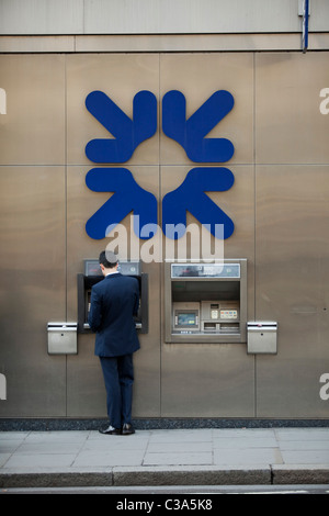 Ein Mann aus eine RBS-Geldautomaten Geld abheben. Stockfoto