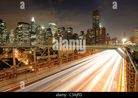 Blick auf Downtown Manhattan von der Brooklyn Bridge mit dem Verkehr von fliegen. Stockfoto