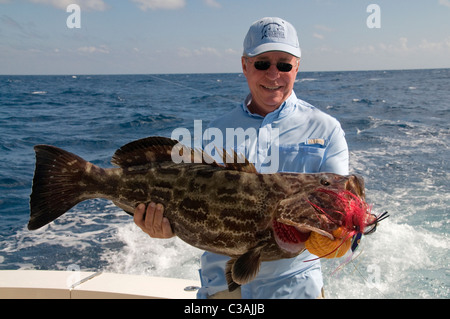 Ein Angler hebt seine netter Fang, eine große Zackenbarsch, gefangen am Strand im Bereich Riviera Maya/Puerto Aventuras Mexiko. Stockfoto