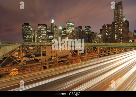 Blick auf Downtown Manhattan von der Brooklyn Bridge mit dem Verkehr von fliegen. Stockfoto