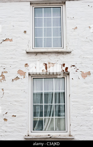 Zwei Fenster in eine weiß gestrichene Wand. Die Lackierung ist verfallen und blätterte von der Wand aufgrund der Exposition gegenüber am Meer Wetter. Stockfoto