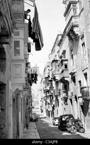 Frau, hängen die Wäsche zum Trocknen auf ihren Holzbalkon am Hospital Street in der maltesischen Hauptstadt Valletta. Stockfoto