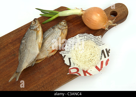 Getrockneter Fisch, Zwiebeln und Salz auf einem Brett auf einem weißen Hintergrund Stockfoto