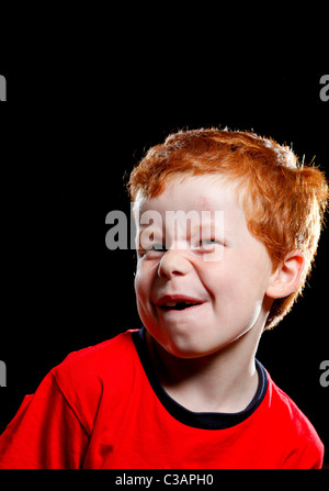 Ein sieben Jahre alter Junge ziehen ein lustiges Gesicht in Richtung der Kamera. Stockfoto