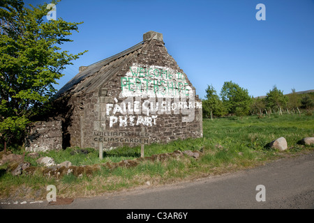 In Perthshire Abandoned Scottish Country Cottage mit Slogan "Freie Schottland "Willkommen in Gälisch auf dem Giebel gemalt. Politische Schriften, am Straßenrand Stockfoto