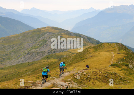 Drei Mountainbiker fahren entlang einer Strecke auf einem Bergrücken hoch hinauf in das Skigebiet von Méribel in Frankreich. Stockfoto