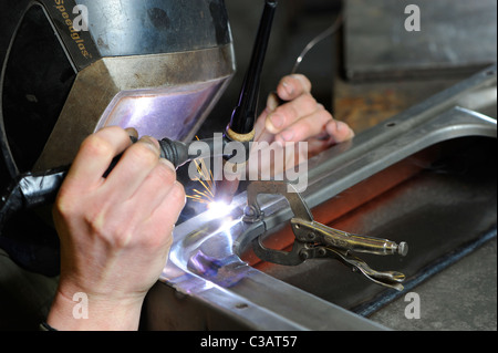 Metall Facharbeiter bei Arbeiten Metalle, mit WIG-Schweißen Methode, um eine Reparatur an einem VW Camper Tür zu machen. Stockfoto
