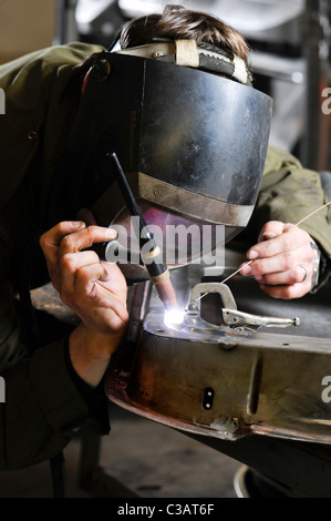 Metall Facharbeiter bei Arbeiten Metalle, mit WIG-Schweißen Methode, um eine Reparatur an einem VW Camper Tür zu machen. Stockfoto