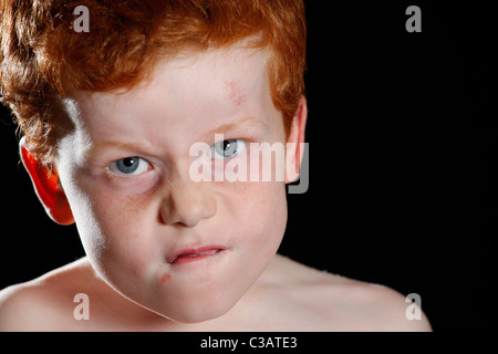 Ein sieben Jahre alter Junge ziehen ein lustiges Gesicht in Richtung der Kamera. Stockfoto