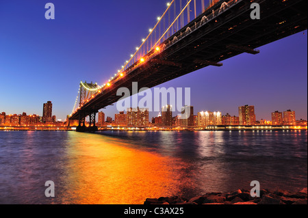 New York City Manhattan Bridge über den East River an der Dämmerung Licht mit Reflexionen und die Skyline der Innenstadt aus gesehen Stockfoto