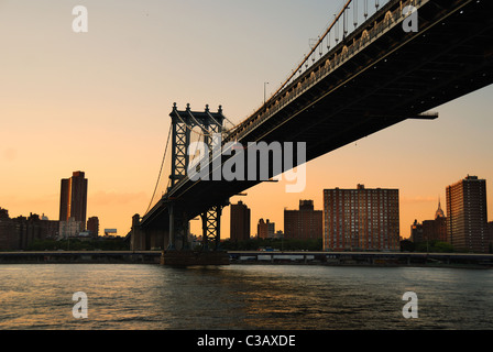 New York City Manhattan Bridge über den Hudson River mit Skyline nach Sonnenuntergang Nachtansicht mit Lichtern beleuchtet aus Brooklyn angesehen. Stockfoto