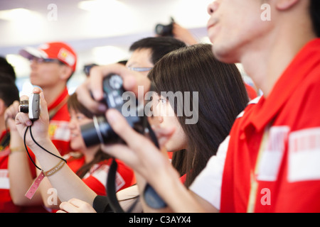 Shanghai: schöne junge Frau hält eine Kamera im Ferrari Paddock Stockfoto