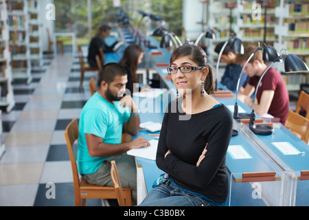 Porträt des weiblichen College-Student auf Tisch in Bibliothek und Blick in die Kamera. Horizontale Form, Hüfte aufwärts Stockfoto