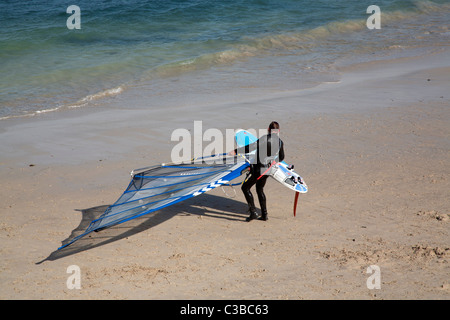 Windsurfer ziehen Board an den Strand am Porthmeor Beach St Ives Cornwall, UK Stockfoto