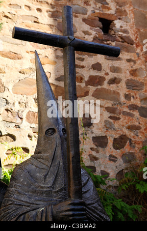 Statue von einem reuigem (Nazareth) in einer spitzen Haube (Capirote) trägt ein Kruzifix in Cáceres, Extremadura, Spanien. Stockfoto