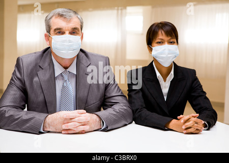 Porträt von zwei Geschäftspartnern in Schutzmasken Blick in die Kamera Stockfoto