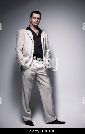 In voller Länge Portrait ein hübscher junger Mann stehend mit Hishands in der Tasche. Stockfoto