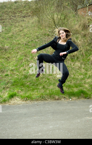 Kaukasische Mädchen tun, Tae Kwon Kampfsport-Kicks auf Pfad in der Nähe von Emersons Grün in Bristol uk Stockfoto