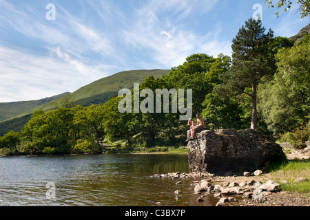 Loch Voil in Balquhidder Glen, Teil des Loch Lomond und Trossachs Nationalpark, Schottland mit 2 Personen saßen auf großen Felsen Stockfoto