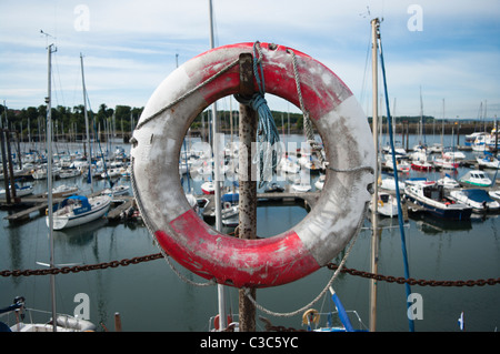 Ein Alter Rettungsring an einem Yachthafen mit Yachten im Hintergrund. Stockfoto