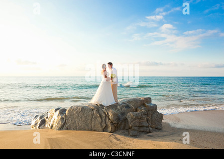 Brautpaar am Strand umarmt Stockfoto