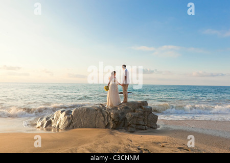 Brautpaar am Strand umarmt Stockfoto