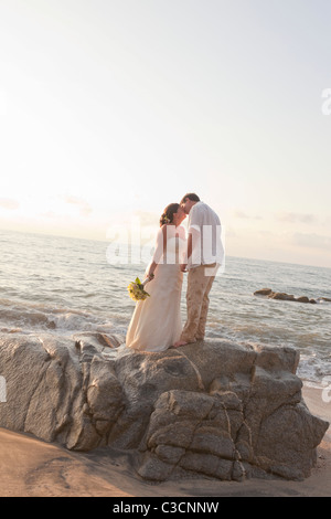 Brautpaar am Strand umarmt Stockfoto