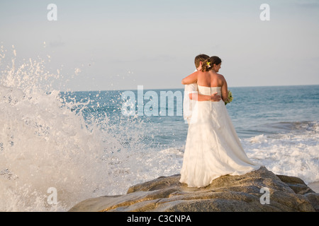 Brautpaar am Strand umarmt Stockfoto