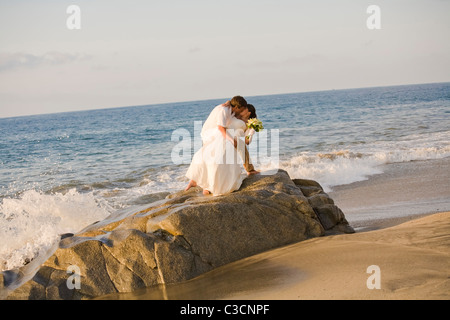 Brautpaar am Strand umarmt Stockfoto