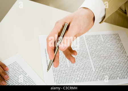 Bild der männlichen Hand mit Kugelschreiber auf Papier während der Erörterung der Pläne Stockfoto