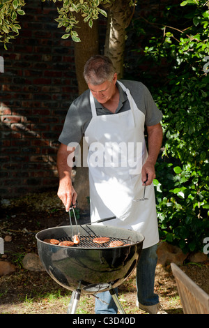 Gut aussehender Mann beim Grillen im Garten Stockfoto