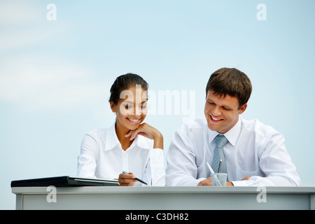 Porträt von Mann und Frau am Schreibtisch sitzen und miteinander interagieren Stockfoto