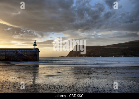 Sandstrand mit Leuchtturm an der Mole-Wand und einem Turm auf den Klippen an einem schönen sonnigen Tag in Port Erin - Isle Of Man Stockfoto