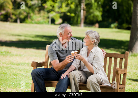 Älteres Paar auf einer Bank ein Eis essen Stockfoto