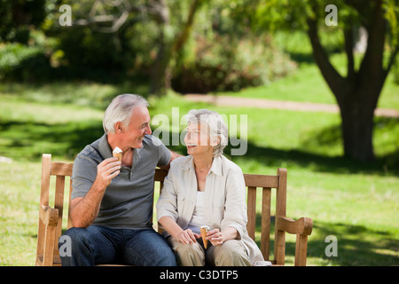 Älteres Paar auf einer Bank ein Eis essen Stockfoto