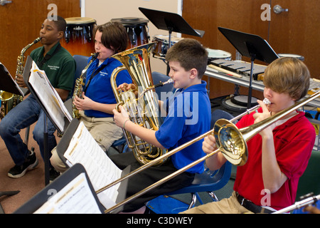 Männliche und weibliche Schülerinnen und Schüler Noten lesen und Euphonium, Posaune und Saxophon zu spielen, während Bandprobe. Stockfoto