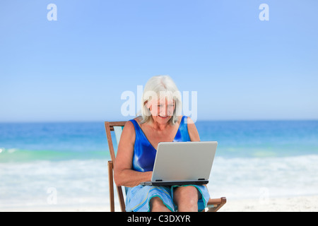 Frau arbeitet auf ihrem Laptop am Strand Stockfoto