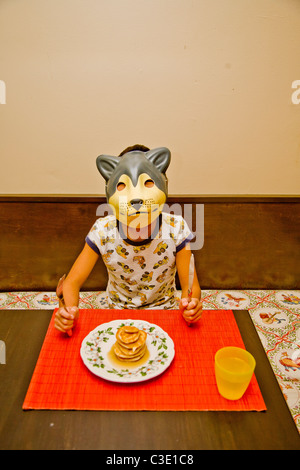 Junge mit Hundemaske am Tisch Stockfoto