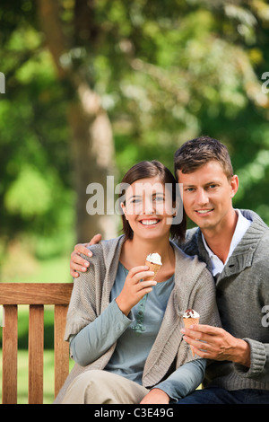 Paar, Essen ein Eis sitzen auf einer Bank Stockfoto