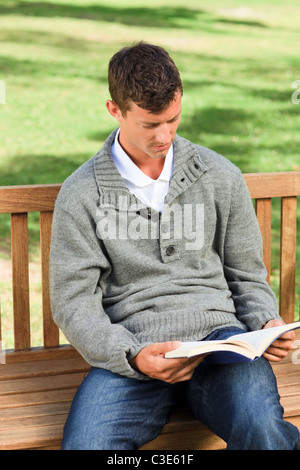 Mann, die Lektüre seines Buches auf der Bank Stockfoto