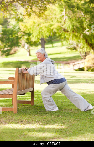 Ältere Frau tut ihr erstreckt sich im park Stockfoto