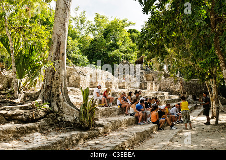 Eine Gruppe von Schülerinnen und Schülern hört eine Anleitung beim Sitzen auf den unteren Stufen der Tempel Struktur bekannt als La Iglesia an die Maya-Stätte von Coba auf der mexikanischen Halbinsel Yucatan. Auf ihrem Höhepunkt Coba schätzungsweise etwa 50.000 Einwohner gehabt haben. Coba Ruinen einer expansiven Maya-Stätte auf der mexikanischen Halbinsel Yucatan, unweit der berühmten Tulum. Eingebettet zwischen zwei Seen, Coba voraussichtlich mindestens 50.000 Einwohner in der prä-kolumbianischen Spitze gewesen. Stockfoto