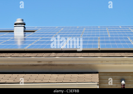 Sonnenkollektoren auf dem Dach des Gebäudes an einem sonnigen blauen Himmel Tag Stockfoto
