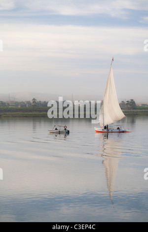 Feluke abgeschleppt mit dem Motorboot auf dem Nil bei Sonnenuntergang, Luxor, Ägypten, Nordafrika Stockfoto